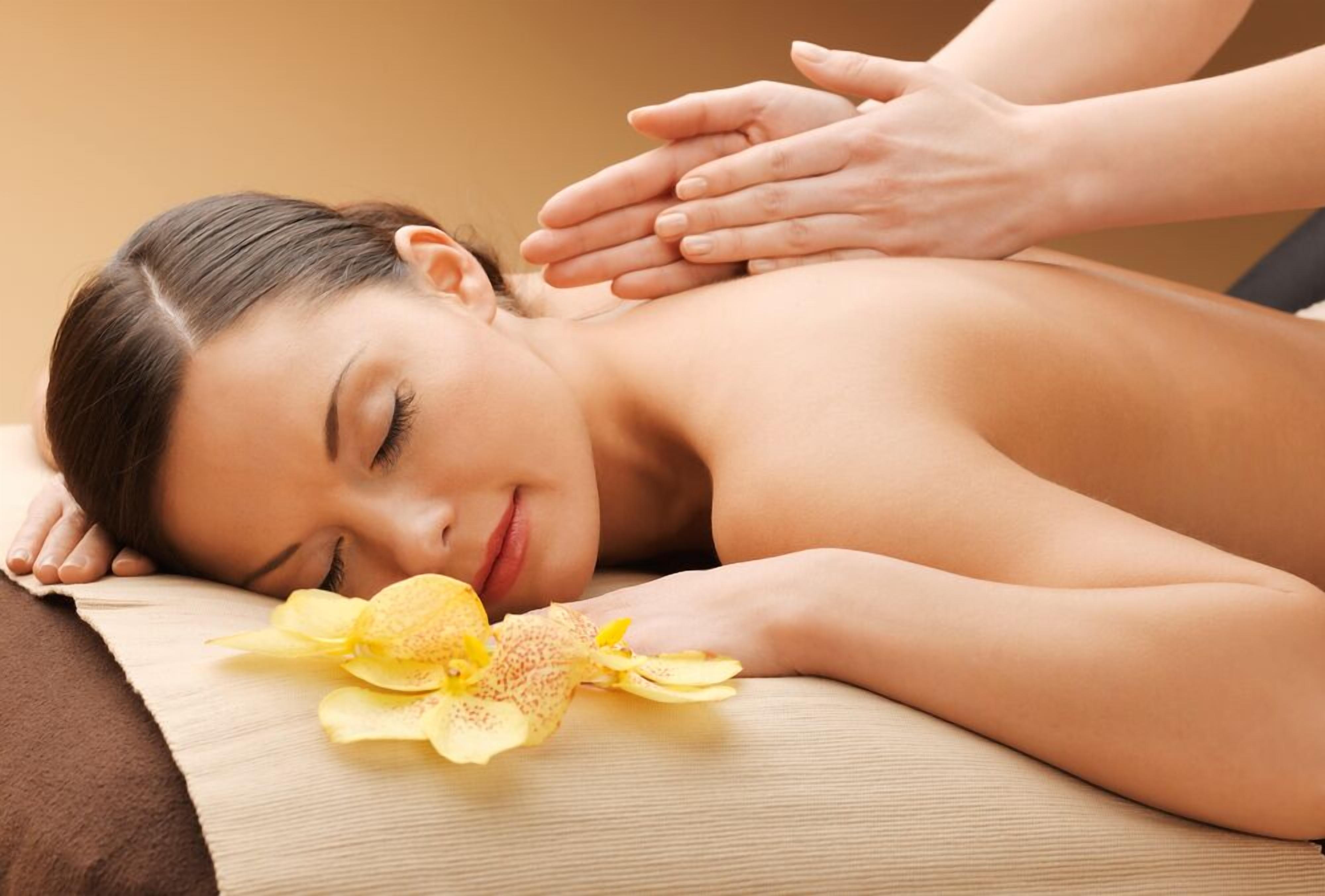 A person receiving a massage with a flower on the massage table.