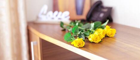 Une étagère en bois ornée d’un bouquet de roses jaunes et d’une plaque décorative sur laquelle est inscrit le mot « Amour ».