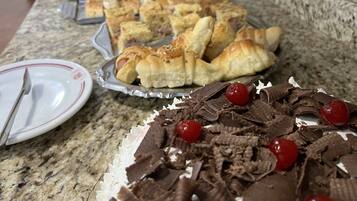 A buffet table with various pastries and desserts, including croissants and chocolate-covered cherries.