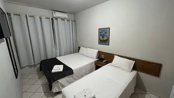 A hotel room with two beds, a nightstand, a telephone, and a painting on the wall.