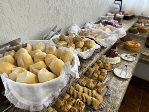 A buffet with various baked goods including bread rolls, pastries, and desserts.