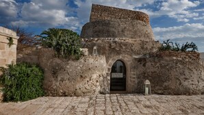 A stone building with a flat roof and an arched entrance. - Masseria Bagnara (Lizzano)
