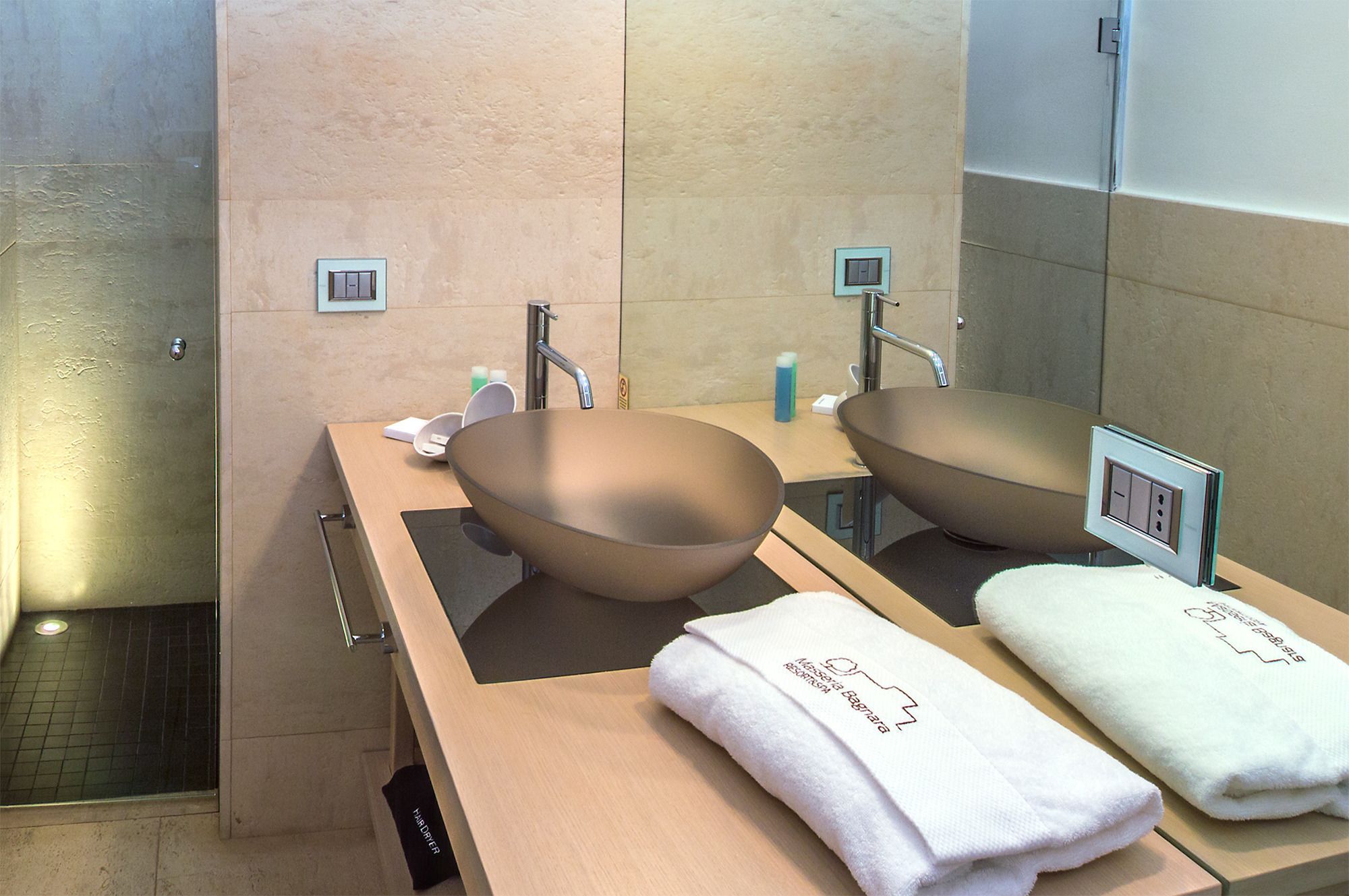 A modern bathroom with a large mirror, two sinks, and a towel rack.