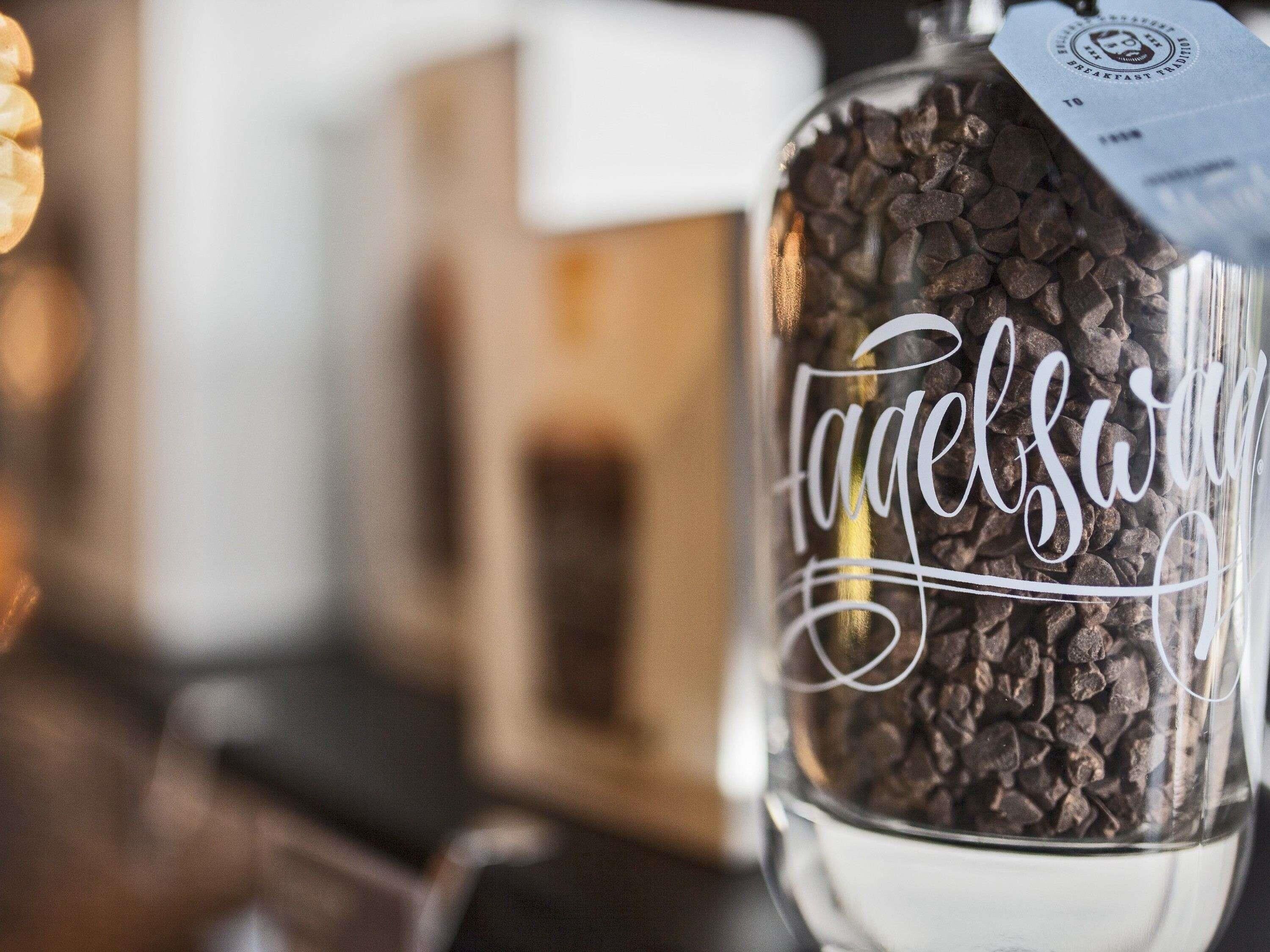 Un bocal en verre rempli de grains de café, étiqueté « Tagelbar ».