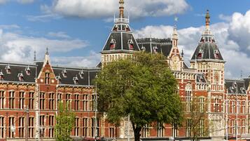 A historic building with multiple towers and a large tree in front.