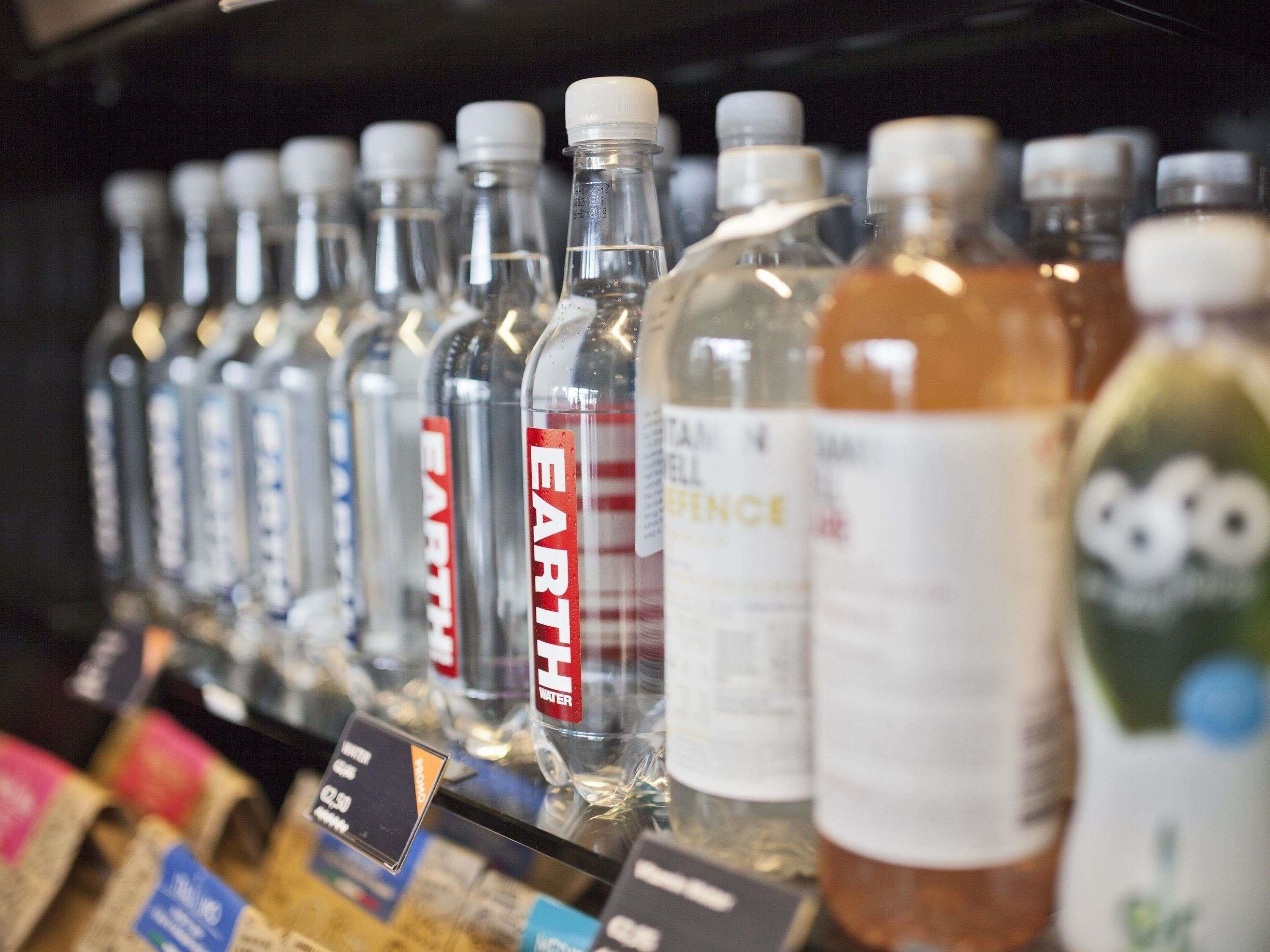 Una estantería con diversas bebidas envasadas, como agua y posiblemente otras opciones, con etiquetas visibles.