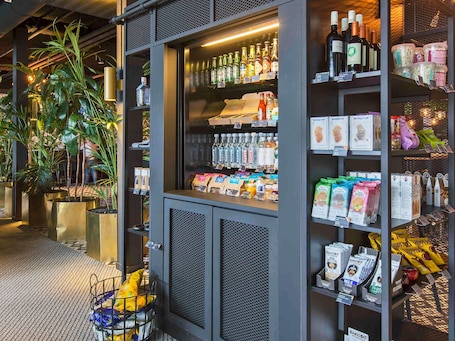 A store with shelves of bottled beverages, packaged snacks, and a display of fresh produce.