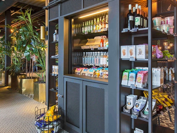 A store with shelves of bottled beverages, packaged snacks, and a display of fresh produce.