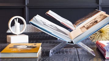 Um livro em um suporte, um espelho decorativo e um livro com capa amarela.