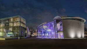 Een modern gebouw met een glazen gevel en een ronde vormgeving.