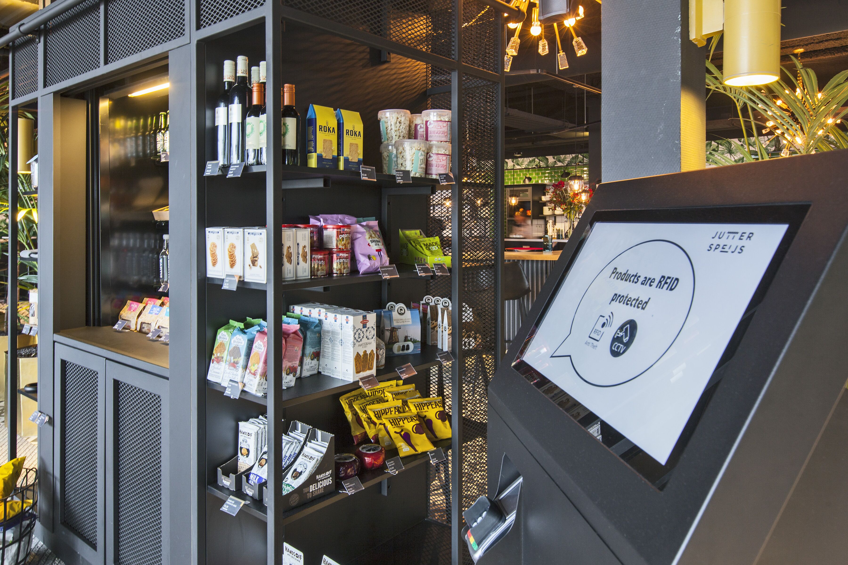 En butiksvisning med hylder fyldt med forskellige produkter, herunder snacks og drikkevarer.