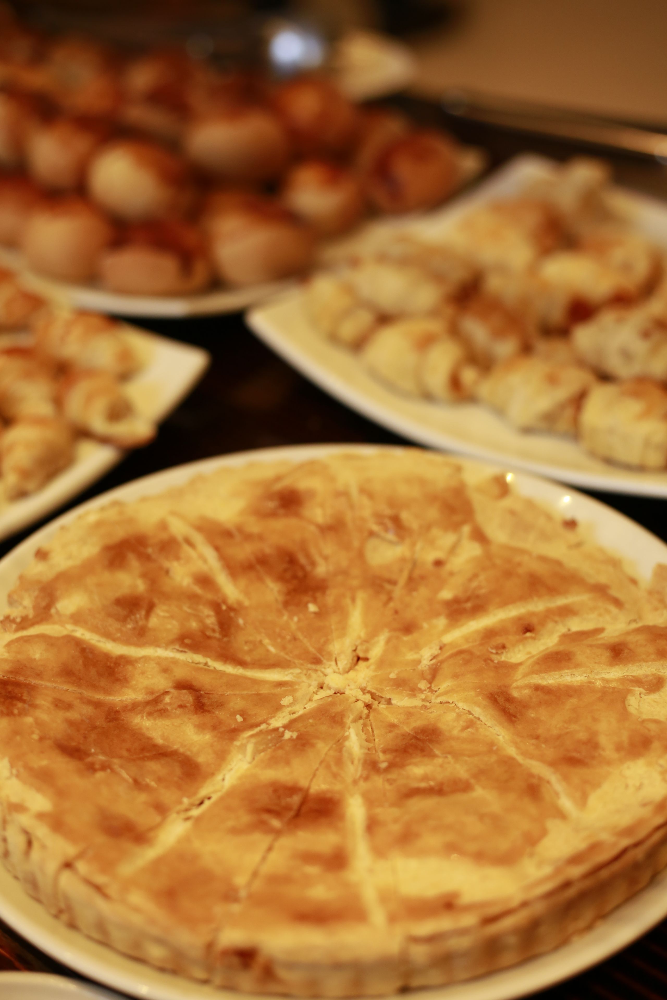 A table with various food items, including a large pie in the foreground.