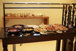 A buffet table with various food items and utensils.