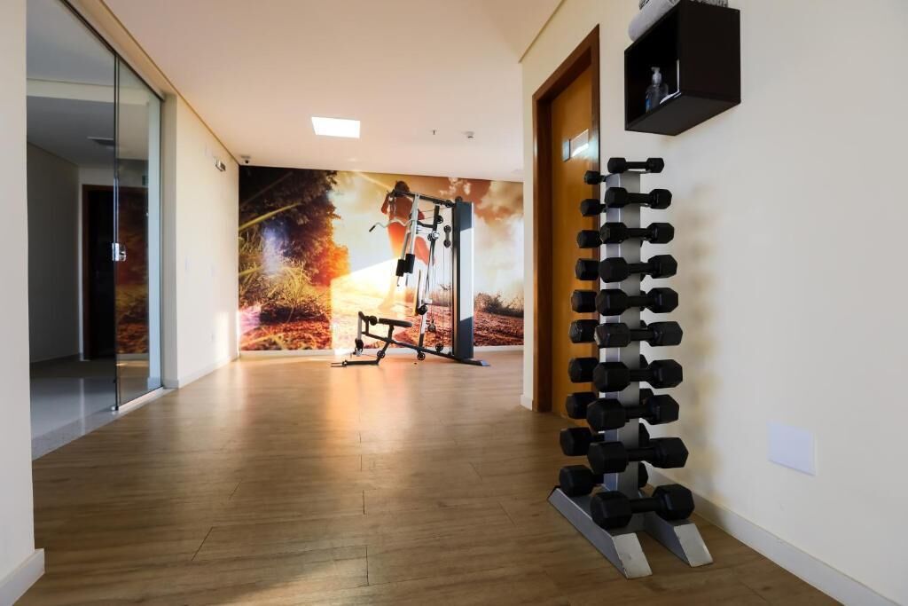 A gym with a wall mural, a row of dumbbells, and a bench.
