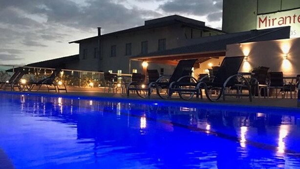 Una piscina con sillas de descanso y un edificio con un letrero que dice "Mirante".