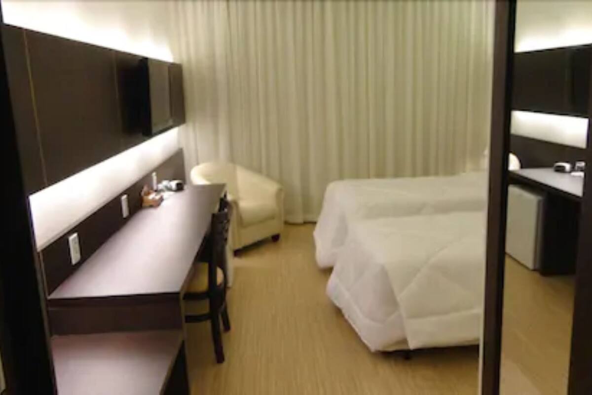 A hotel room with a bed, a desk, a chair, and a television.