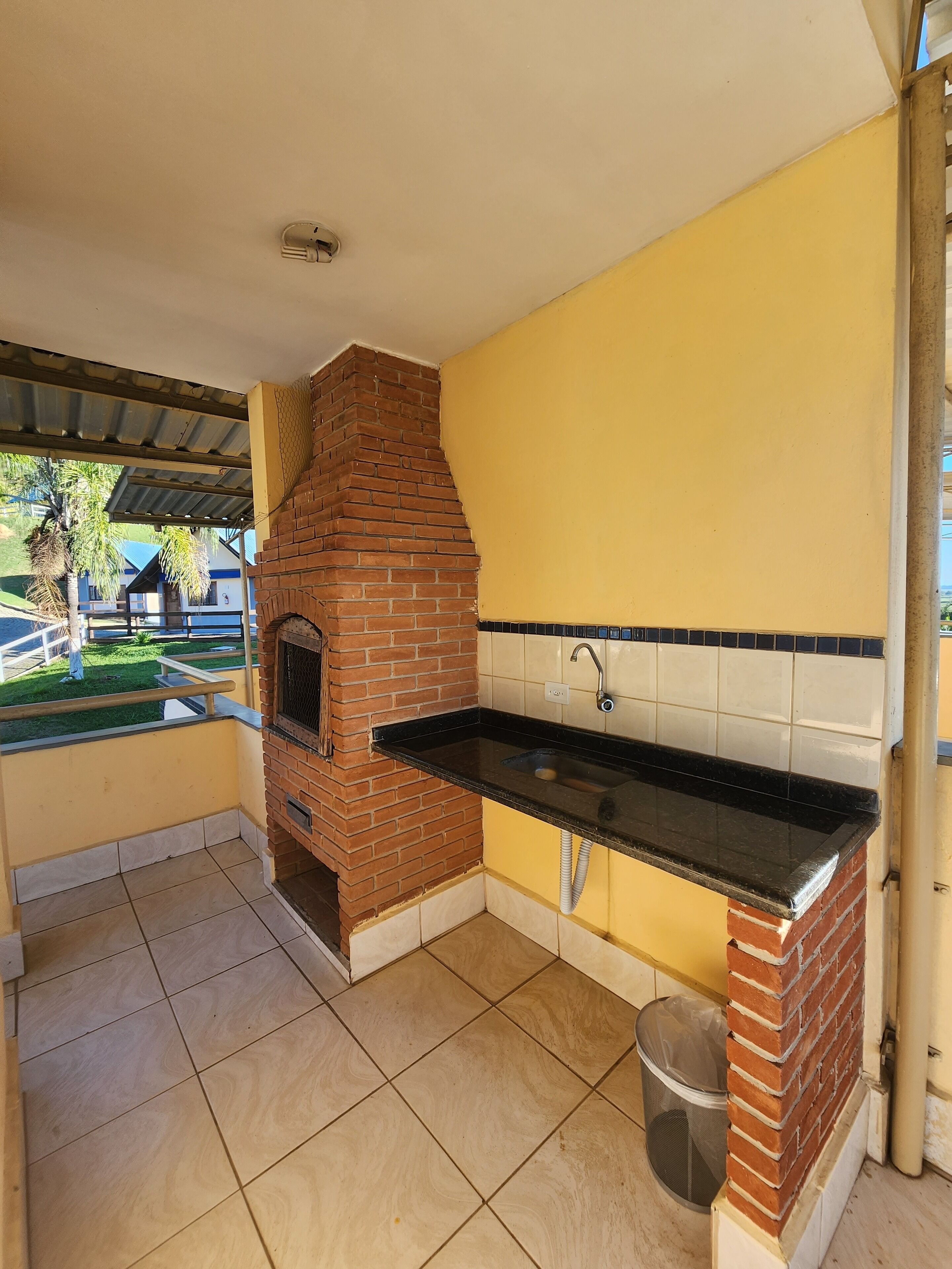 A kitchen with a brick oven, a black countertop, and a tiled backsplash.