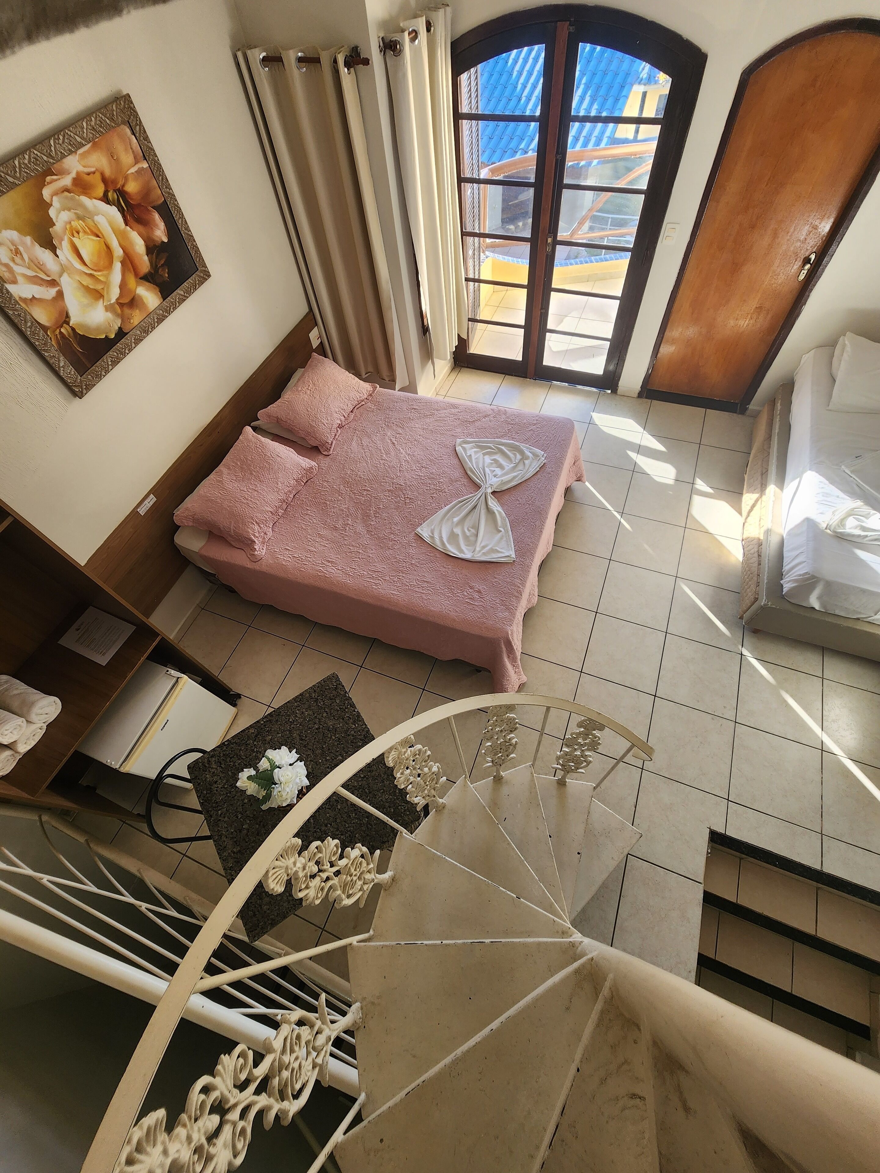 Una camera da letto con un letto, una finestra, una porta e una scala.