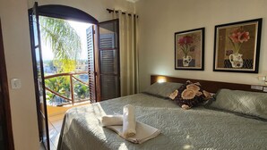 Quarto de hotel com uma cama, vista para o exterior e duas imagens emolduradas na parede.
