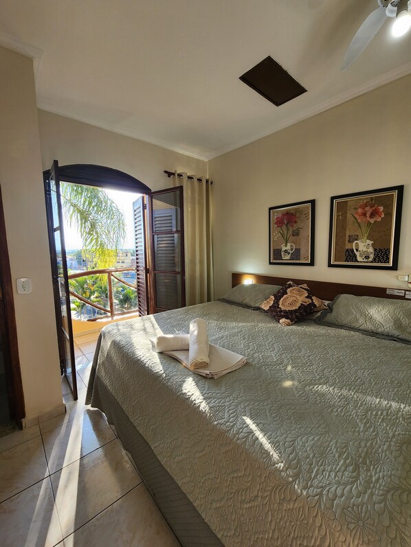 A hotel room with a bed, a view of the outdoors, and two framed pictures on the wall. - Hotel Porto dos Milagres (Aparecida)