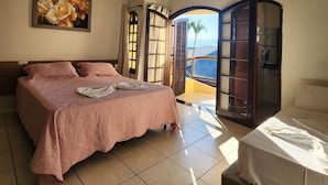 Quarto com uma cama grande, uma cama menor, um quadro na parede e vista para o exterior.