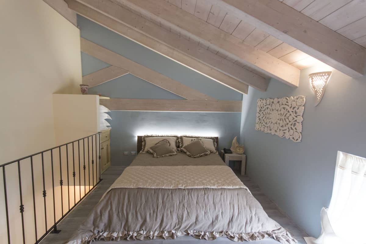 A bedroom with a large bed, a nightstand, a dresser, and a decorative wall piece.