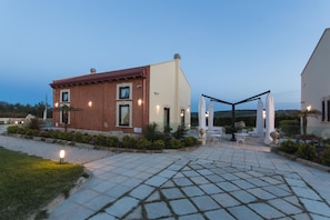 A modern house with a patio area featuring outdoor furniture and a well-maintained garden. - Palascia Wellness Relais (Otranto)