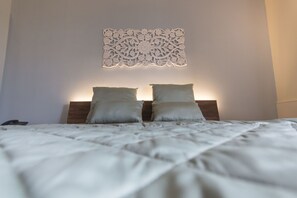A neatly made bed with a headboard, two pillows, and a decorative wall piece above it. - Palascia Wellness Relais (Otranto)