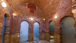 A hallway with brick walls, arched doorways, and checkered flooring. - Hostal Rural Gloria (Cortes y Graena)