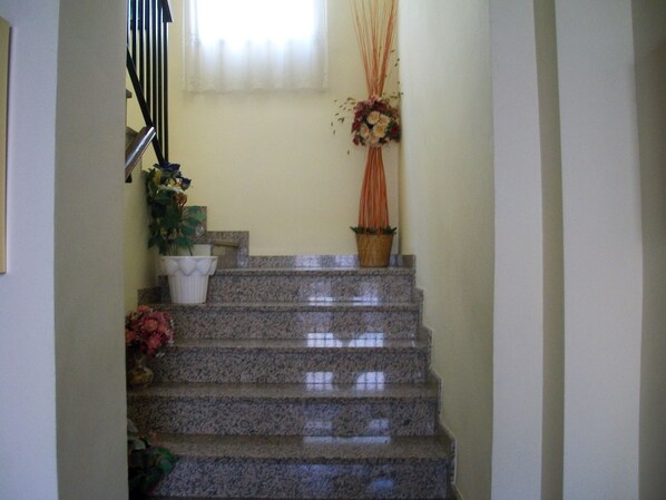 Una escalera con escalones de granito, una planta en maceta y un jarrón con flores.
