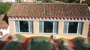 A building with a tiled roof, large windows, and a brick facade. - Hostal Rural Gloria (Cortes y Graena)