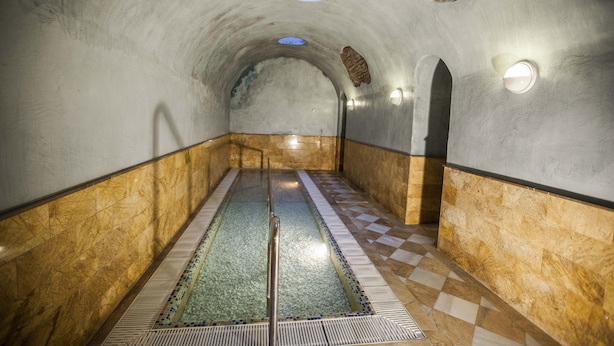 A tunnel-like interior with a checkered floor, a central water feature, and stone walls. - Hostal Rural Gloria (Cortes y Graena)