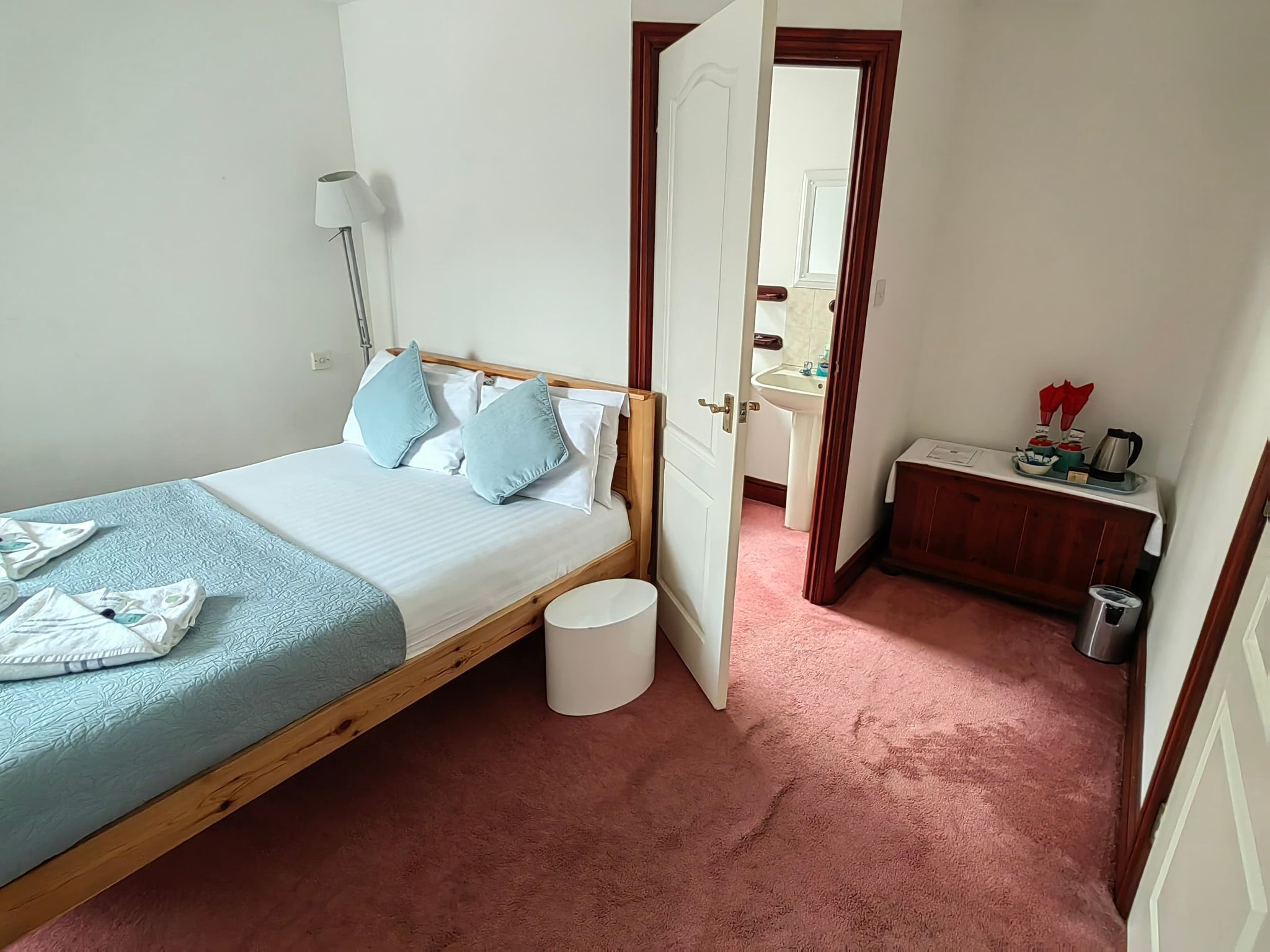 Une chambre à coucher avec un lit en bois, une lampe de chevet, une petite table de chevet et un tapis rose.
