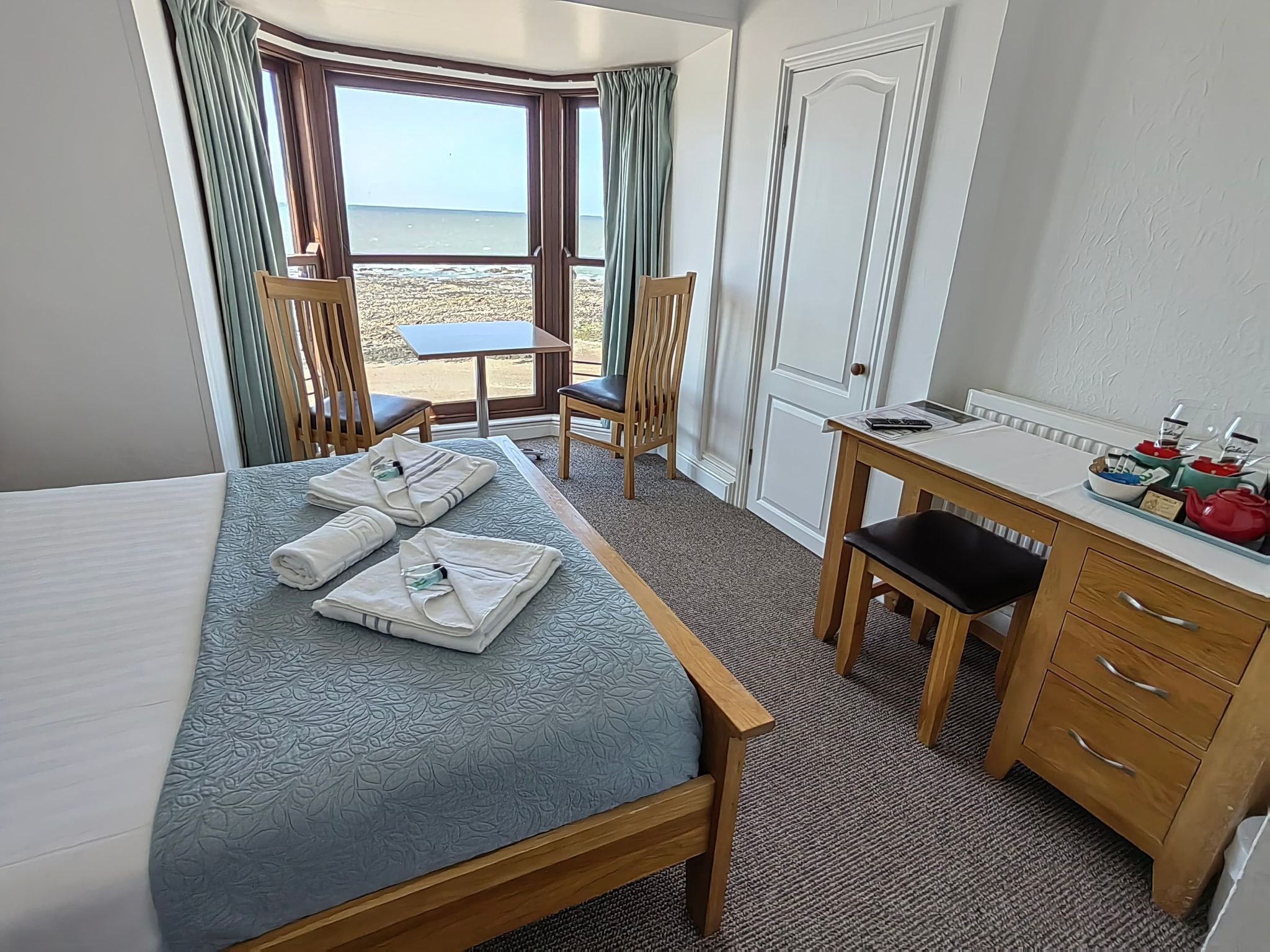 Una habitación de hotel con cama, escritorio, silla y vista a la playa.