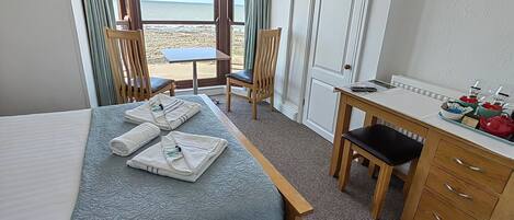 Una habitación de hotel con cama, escritorio, silla y vista a la playa.