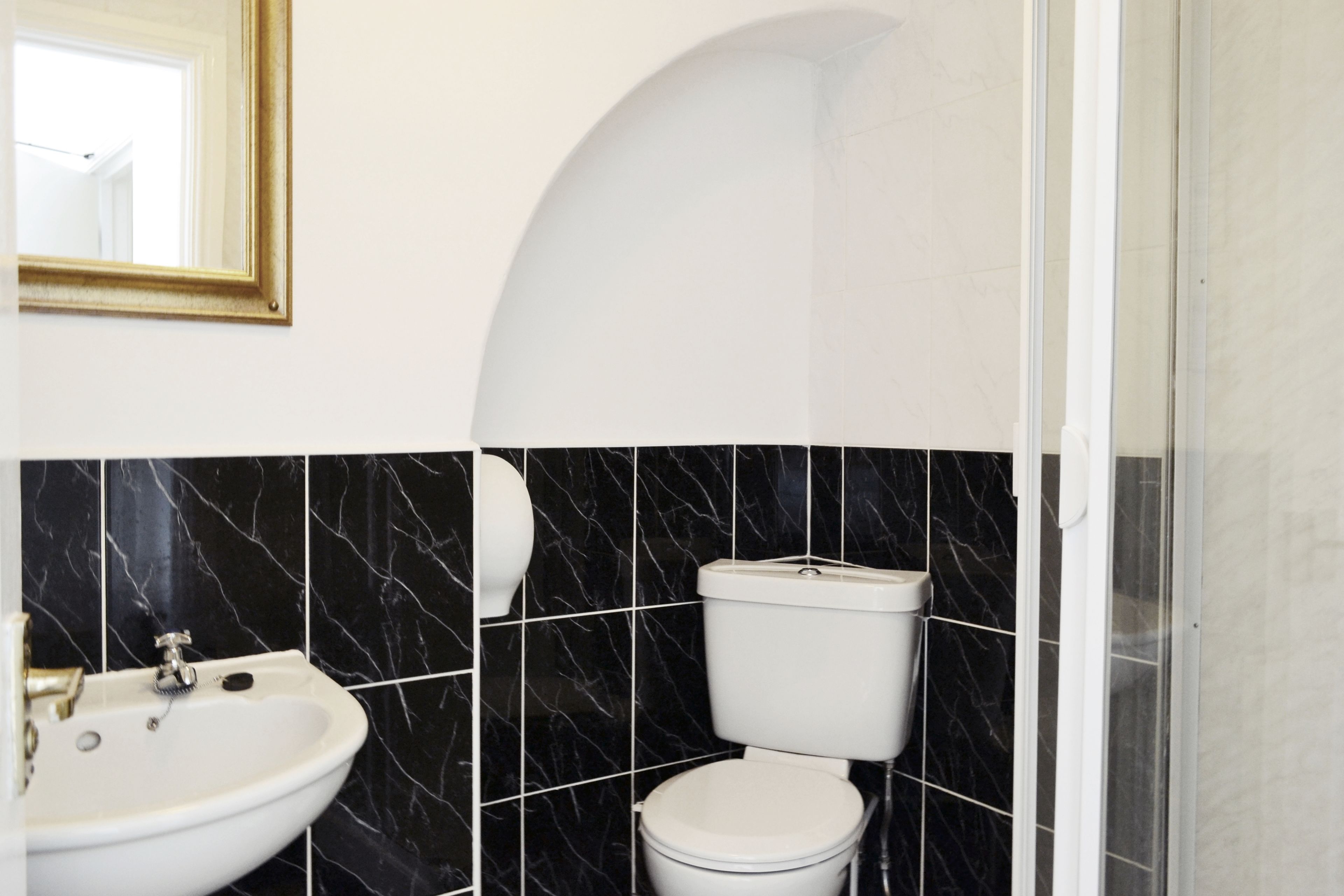 A bathroom with a sink, toilet, and a shower area.