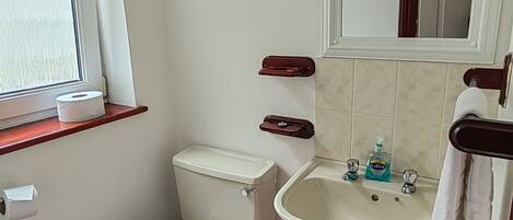 Un baño pequeño con inodoro, lavamanos y espejo.