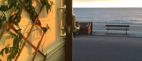 Vista desde un edificio hacia una playa con un banco y un camión.