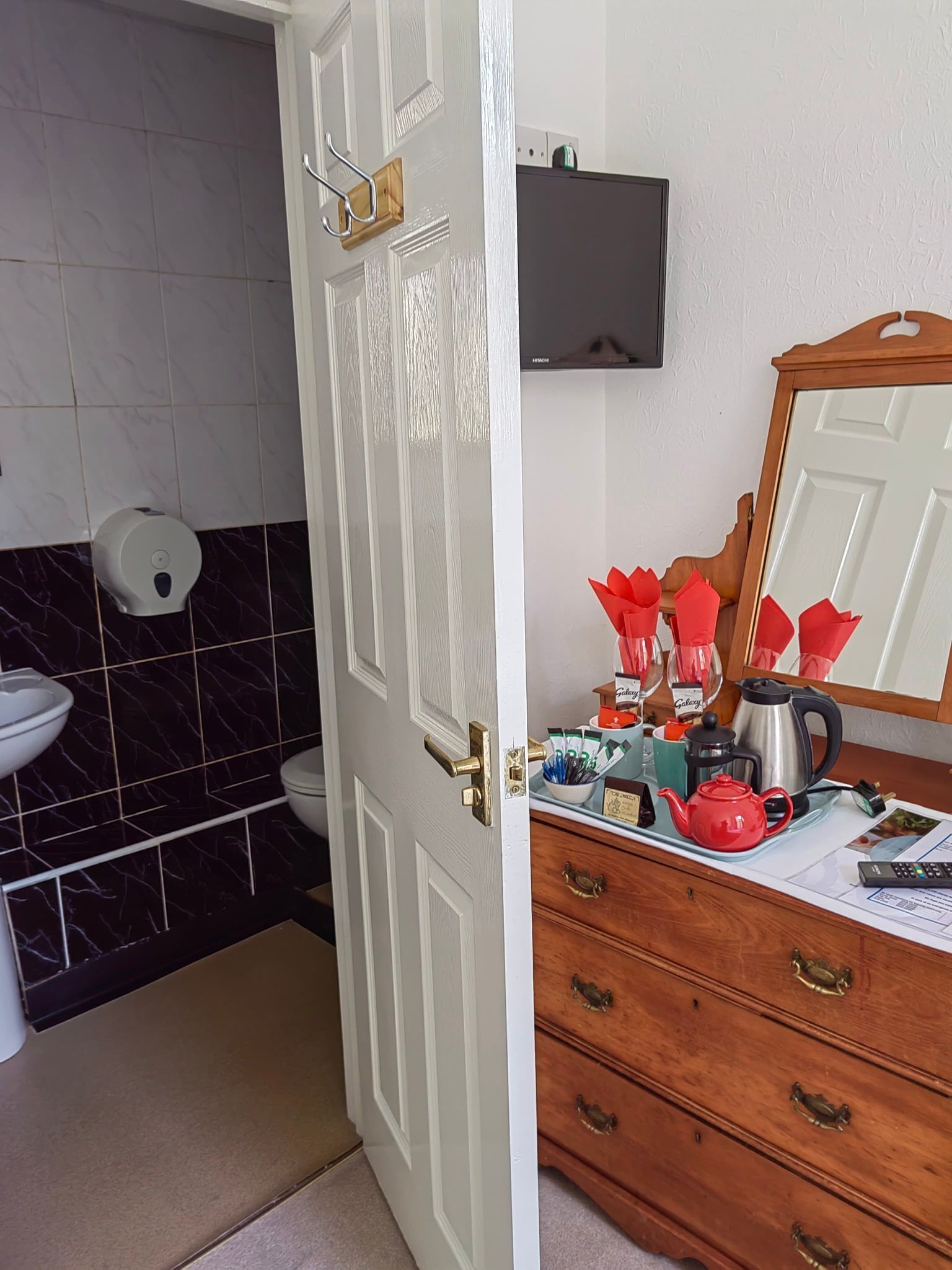 A bathroom with a toilet, sink, and a mirror above a wooden dresser.