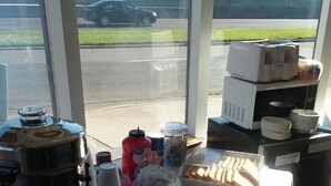 A coffee station with a coffee pot, cups, and condiments. - Sunset Inn (Atlantic City)