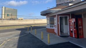 A small, single-story building with a Coca-Cola vending machine and a sign indicating new management. - Sunset Inn (Atlantic City)