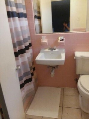 Un baño pequeño con lavamanos, inodoro y cortina de ducha.