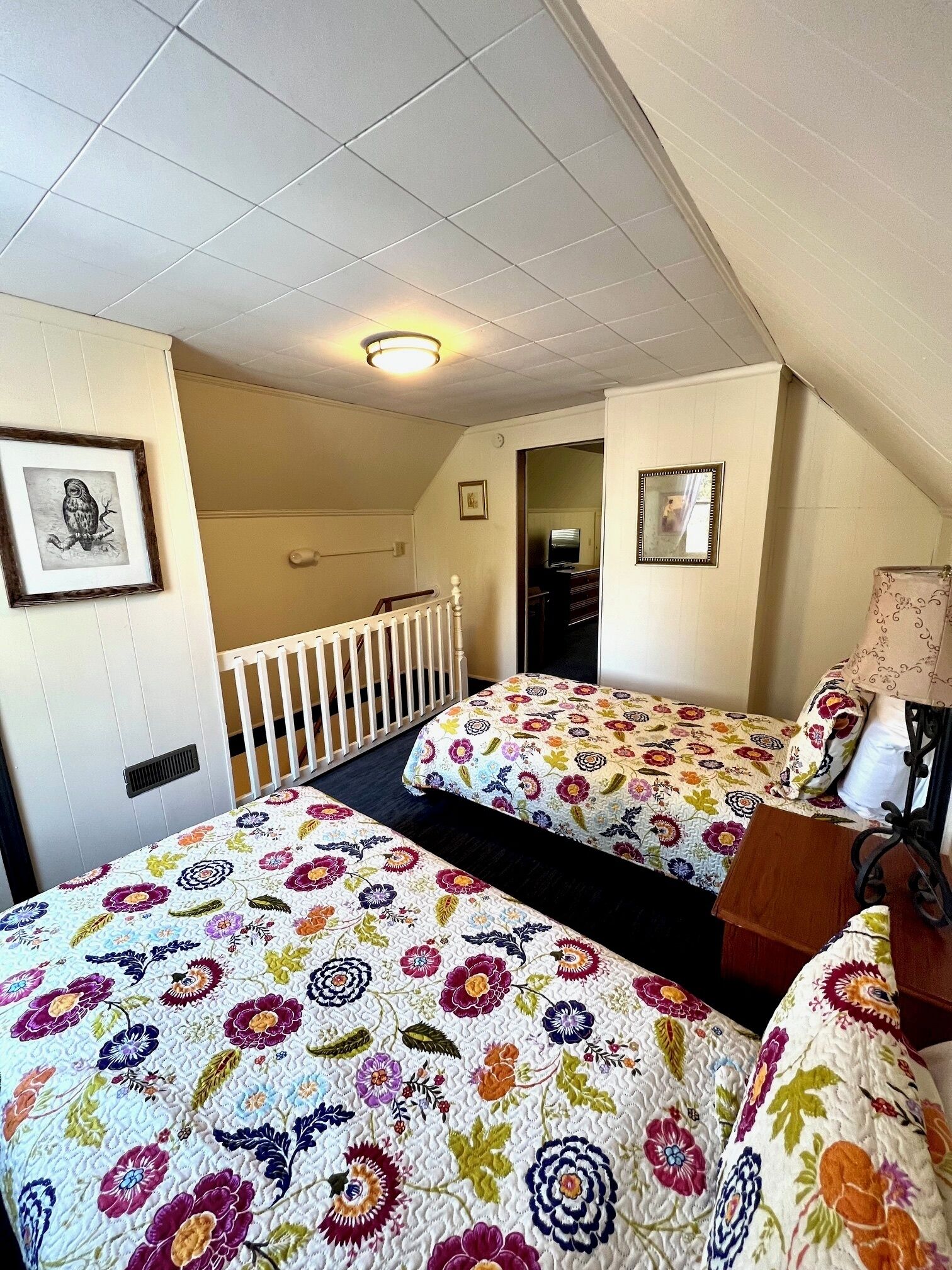 Une chambre avec deux lits, un plafond blanc et une petite fenêtre.