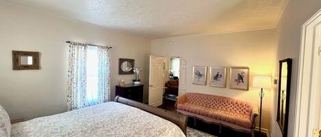 A bedroom with a large bed, a sofa, a dresser, and a mirror.