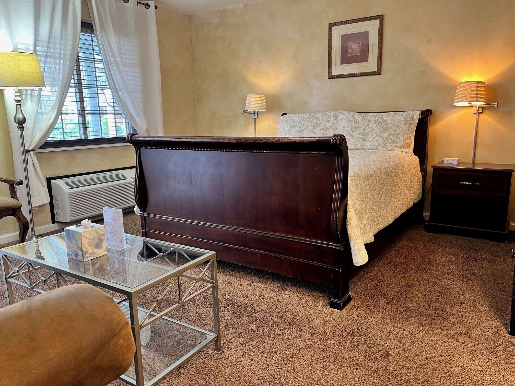 Une chambre à coucher avec un lit en bois, des lampes de chevet, une table en verre et un radiateur.