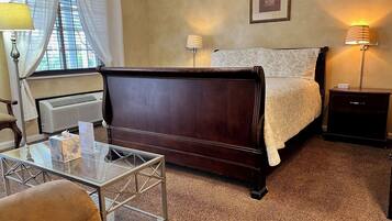 Une chambre à coucher avec un lit en bois, des lampes de chevet, une table en verre et un radiateur.