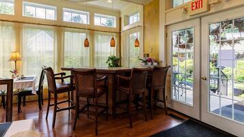 A dining area with a wooden table and chairs, a window with curtains, and an exit sign.