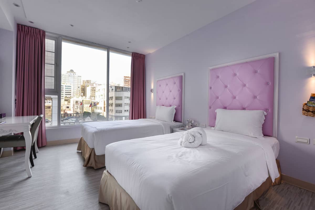 Une chambre d’hôtel avec deux lits, une table à manger et une vue sur la ville.