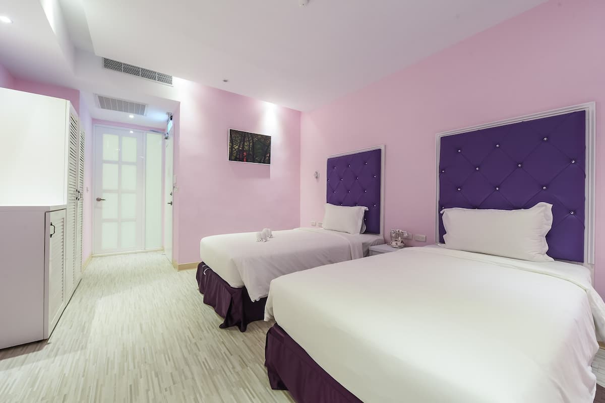 Une chambre d’hôtel avec deux lits, une armoire et une porte donnant sur un couloir.