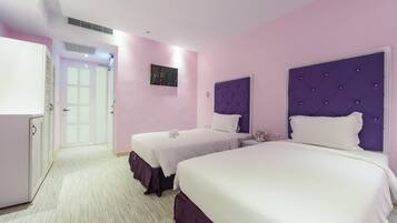 A hotel room with two beds, a wardrobe, and a door leading to a hallway.